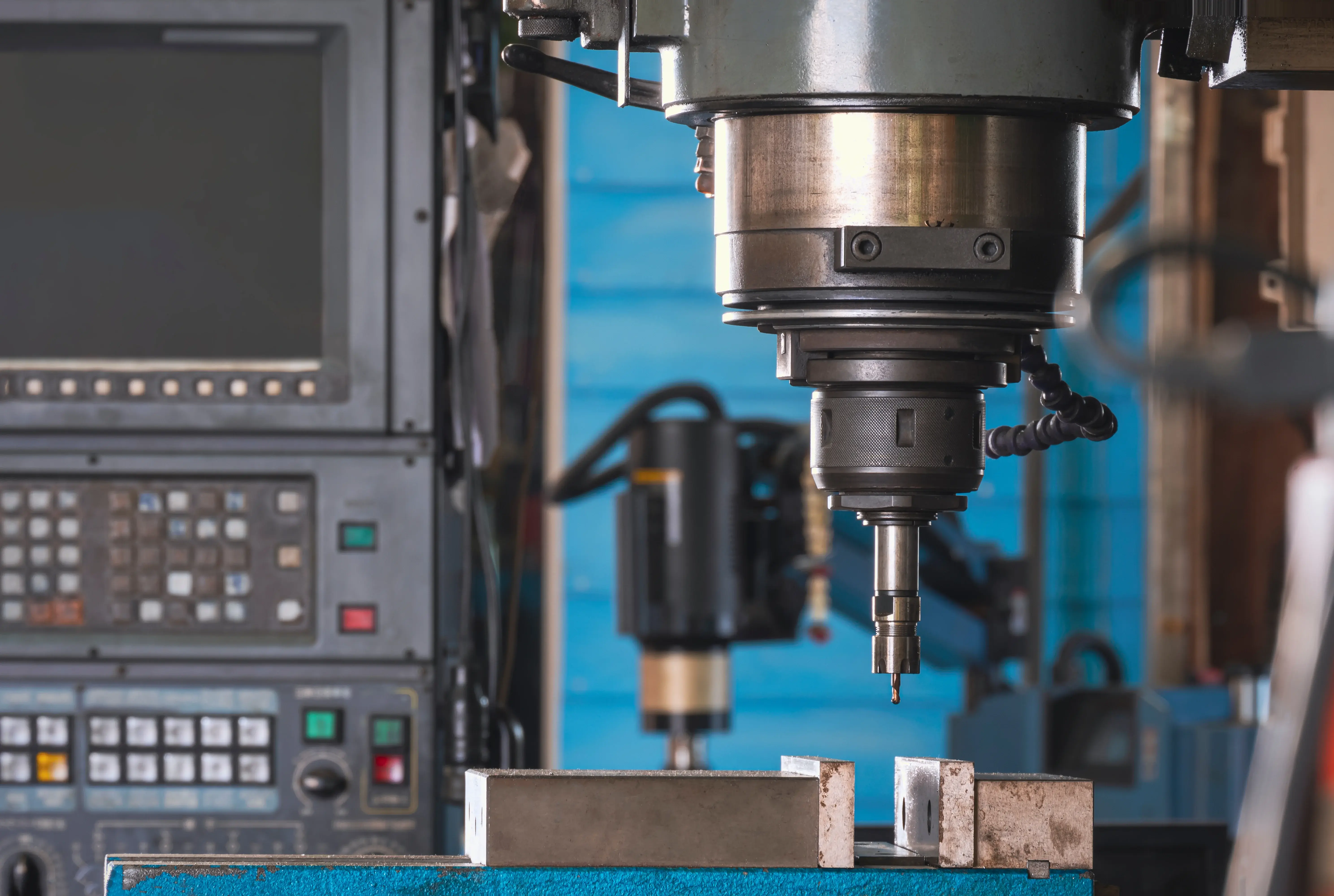 CNC milling machine with digital control panel machining a metal workpiece in a modern precision engineering workshop.